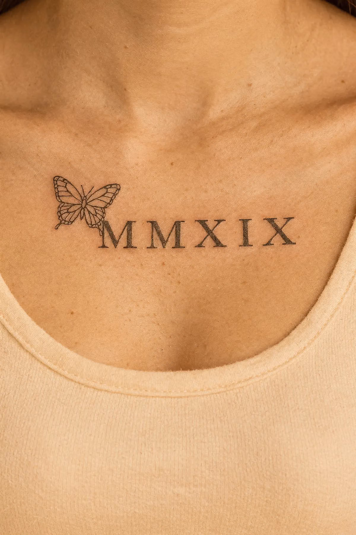 Feinlinien‑Schmetterling und MMXIX in Serif neben dem Schlüsselbein