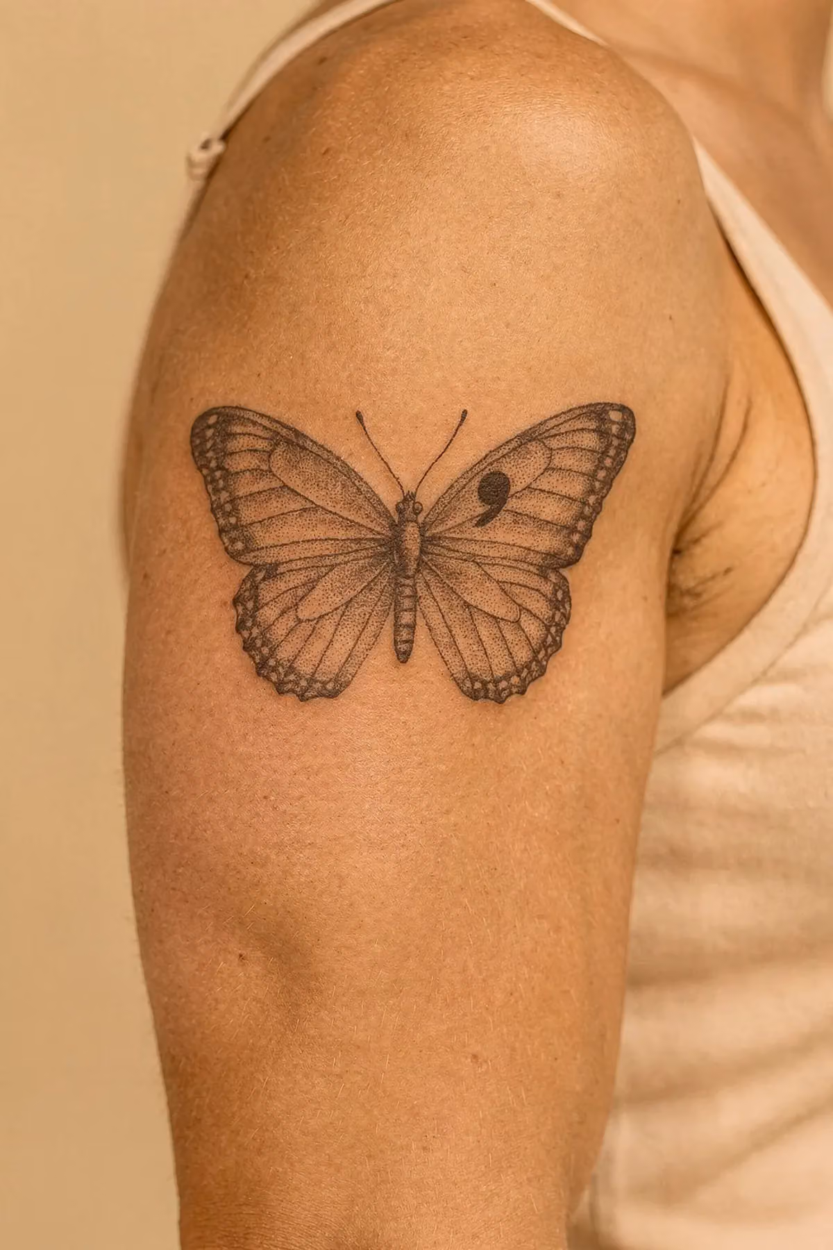Oberarm mit einem Dotwork-Schmetterling, dessen oberer Flügel ein Semikolon als Ader integriert