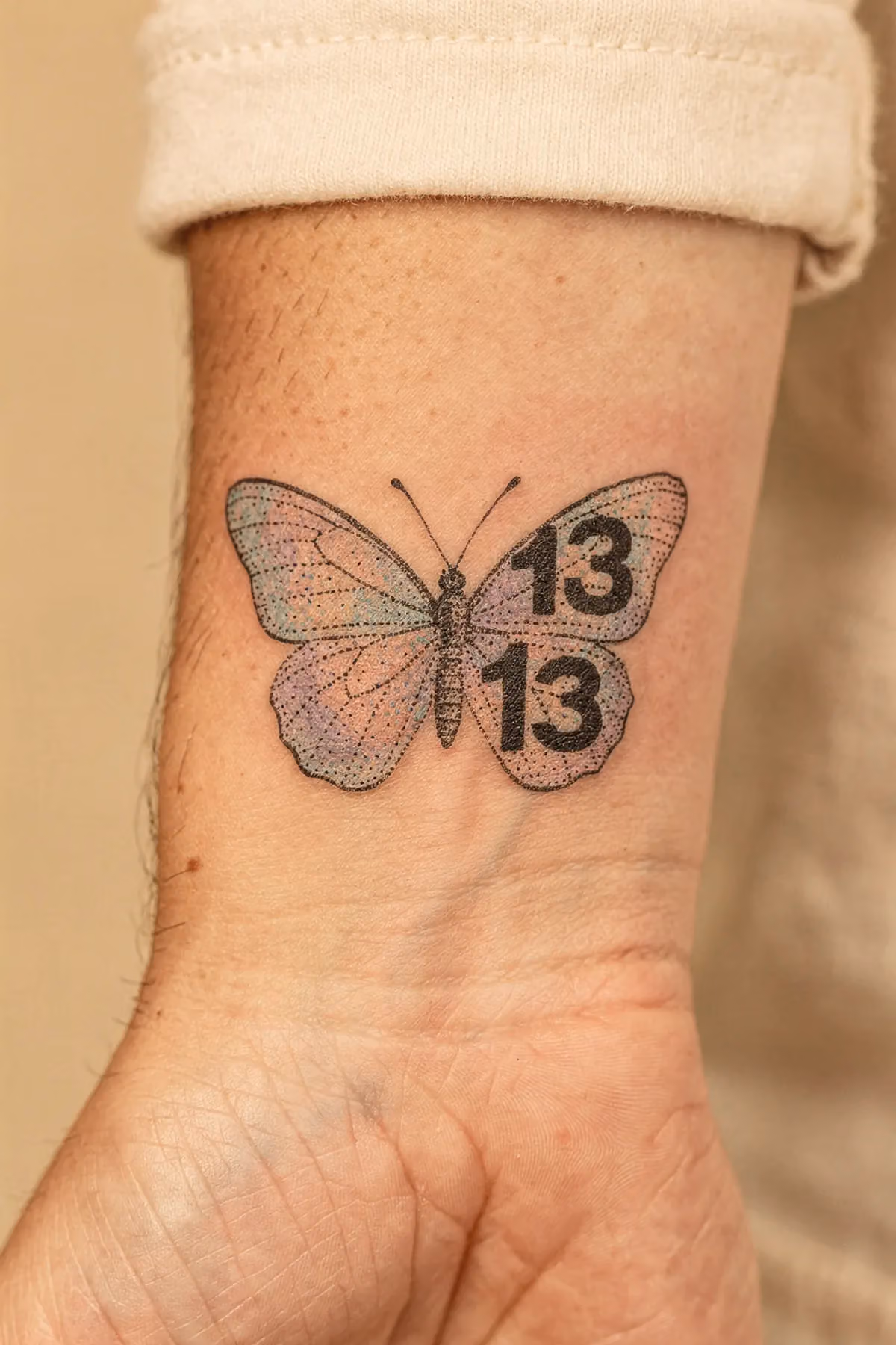 Kleiner Schmetterling am inneren Handgelenk mit Punktmuster‑Zahl 13.