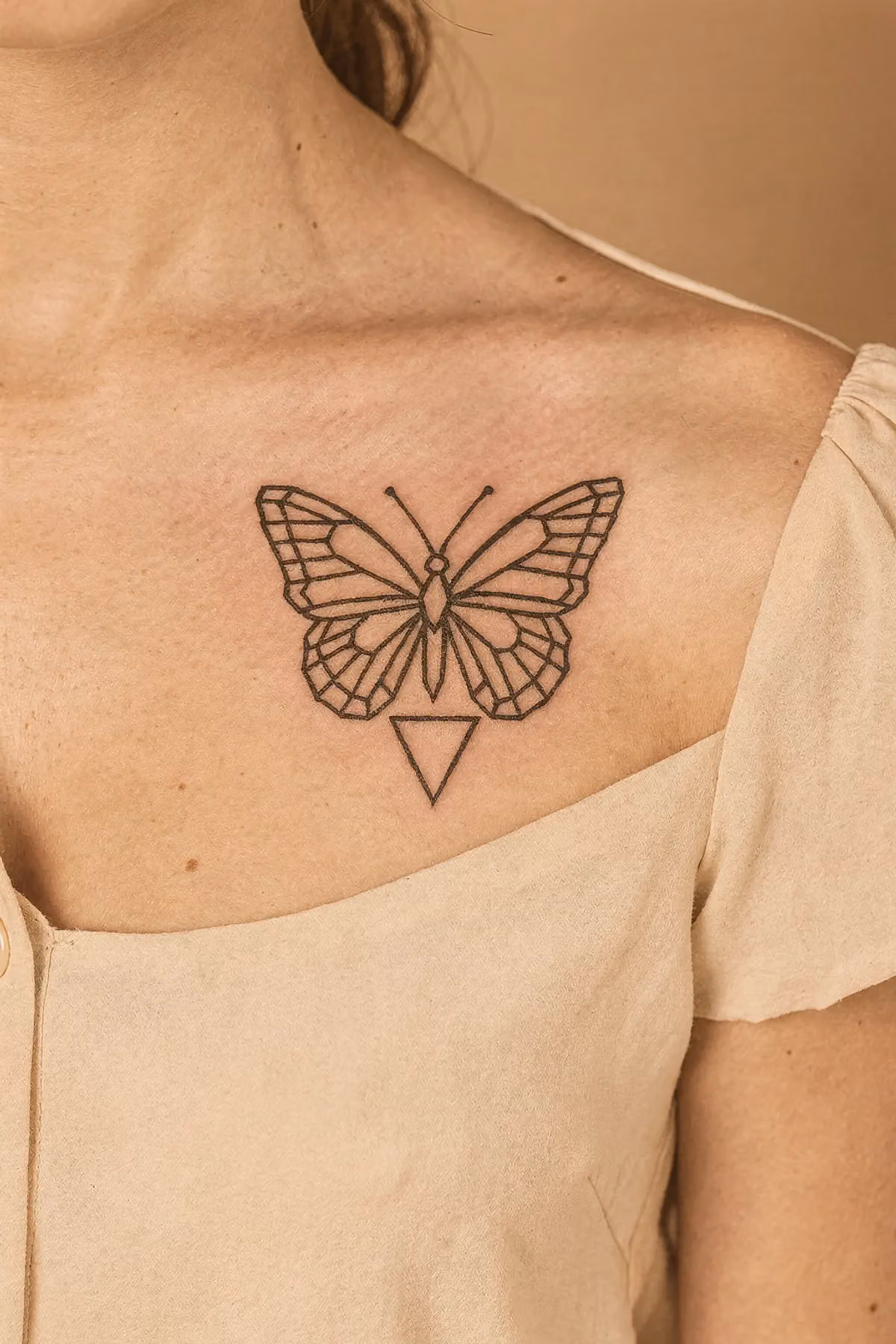 Vordere Schulter und Schlüsselbein mit geometrischem Negativ‑Schmetterling und kleinem Dreieck unterhalb