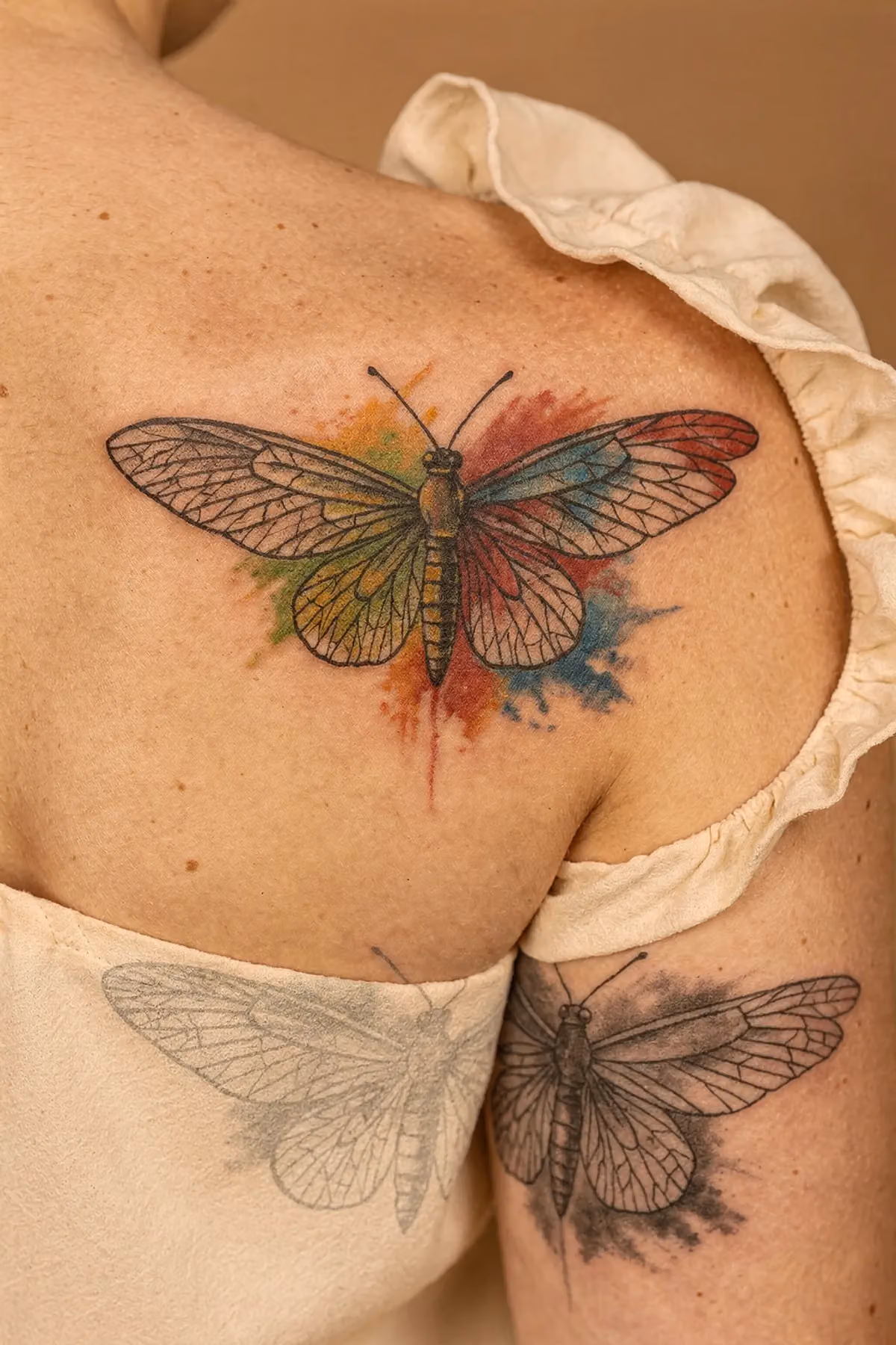 Schmetterlings-Tattoo auf Schulterblatt mit realistischer Flügelzeichnung, Venen und abstrakten Farbfeldern, Graustufen‑Mockup