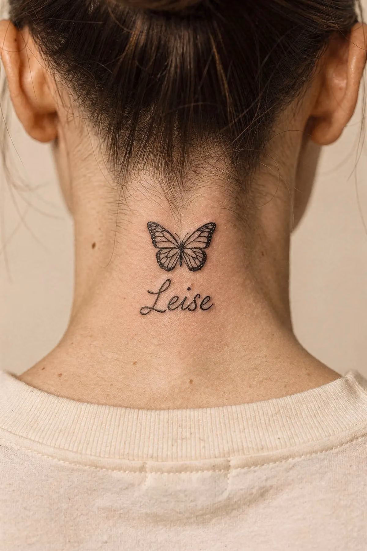 Kleiner Schmetterling im Nacken, darunter das Wort „Leise“ in zarter Schreibschrift.