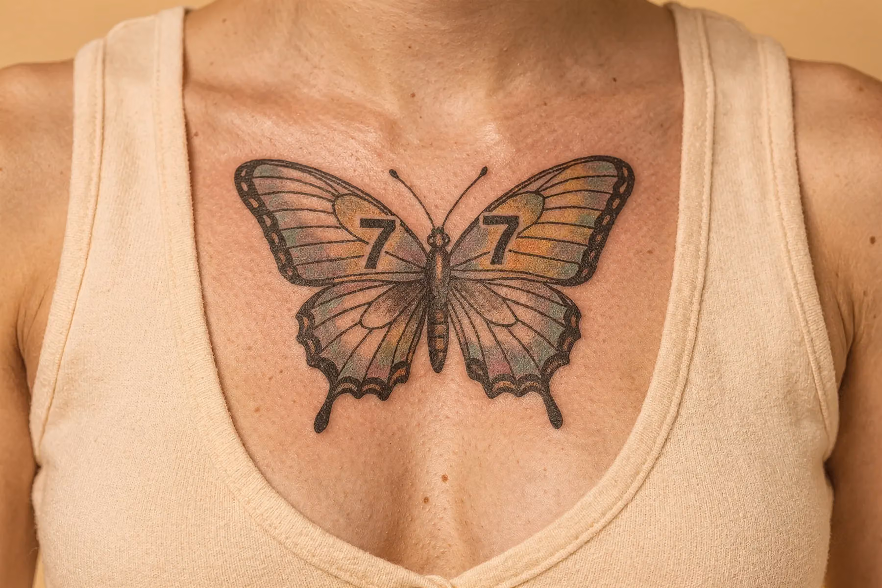 Nahaufnahme eines Schmetterlings-Tattoos mit feinen, in die Flügel integrierten Zahlen auf warmem cremefarbenem Hintergrund.